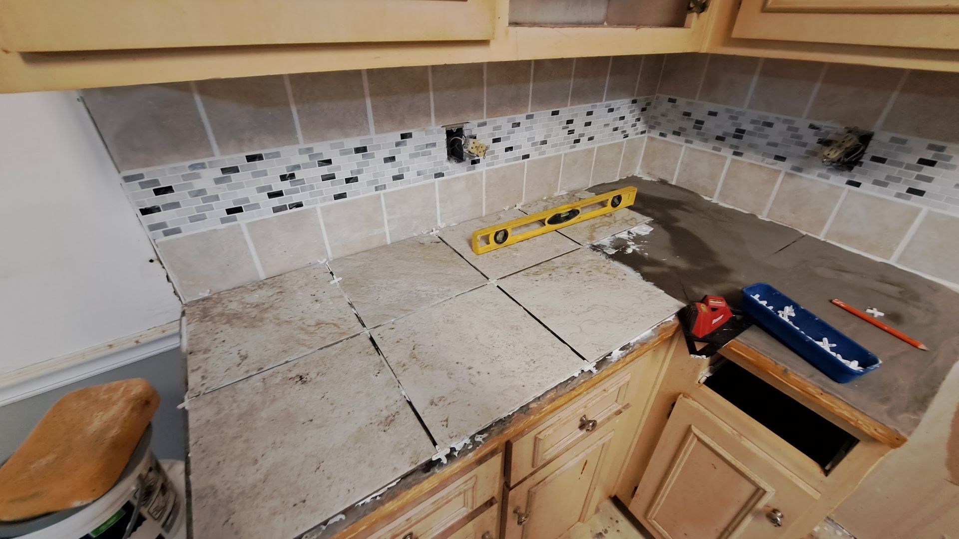 A kitchen counter with tiles being installed and a level on it.