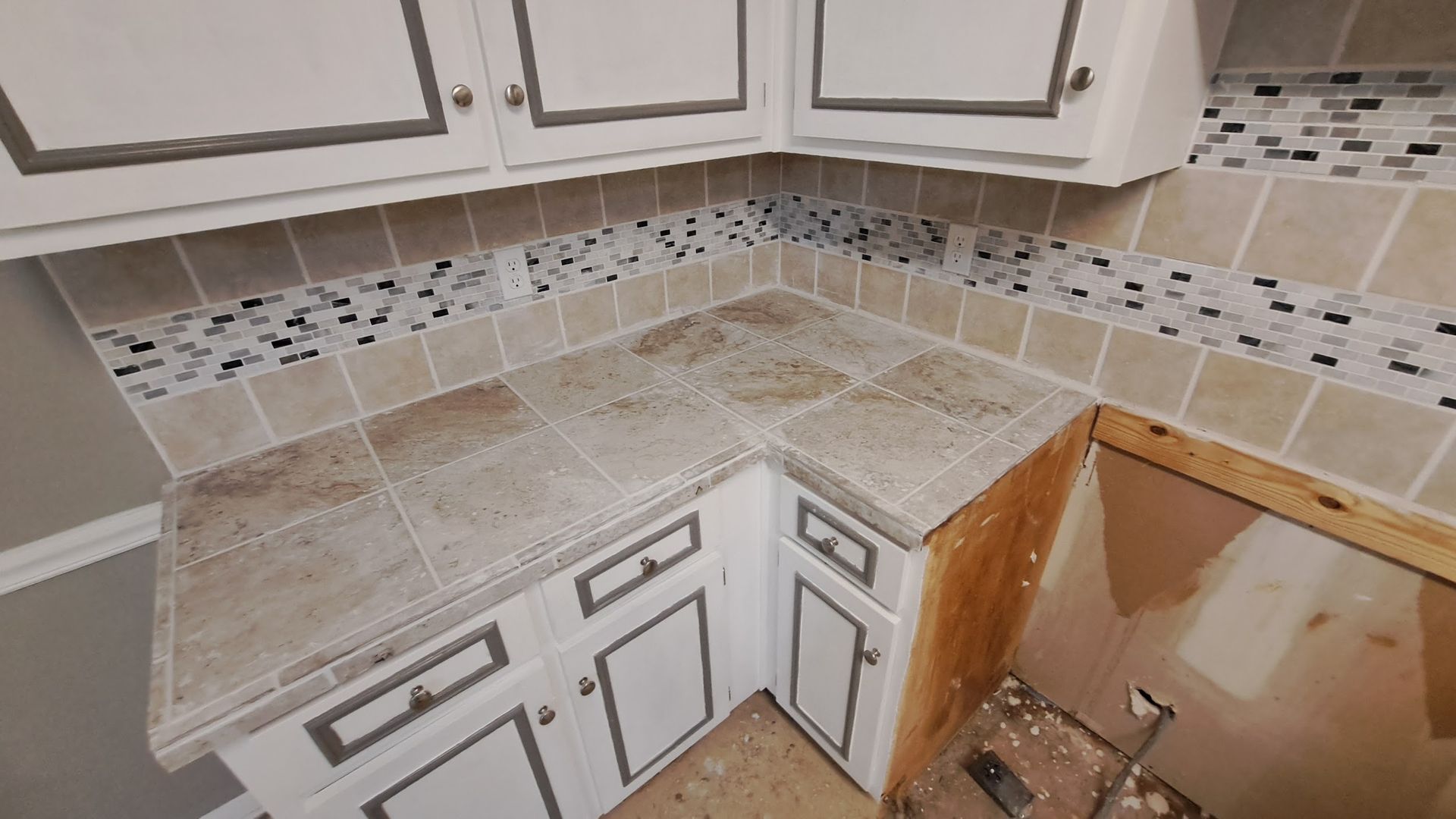 A kitchen with white cabinets and a tiled counter top.