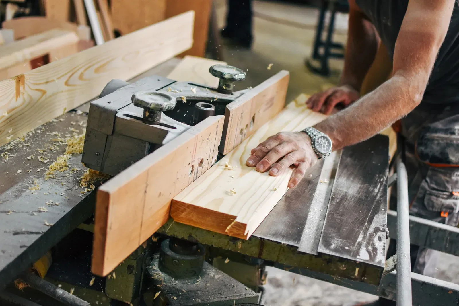 A man is cutting a piece of wood on a machine.