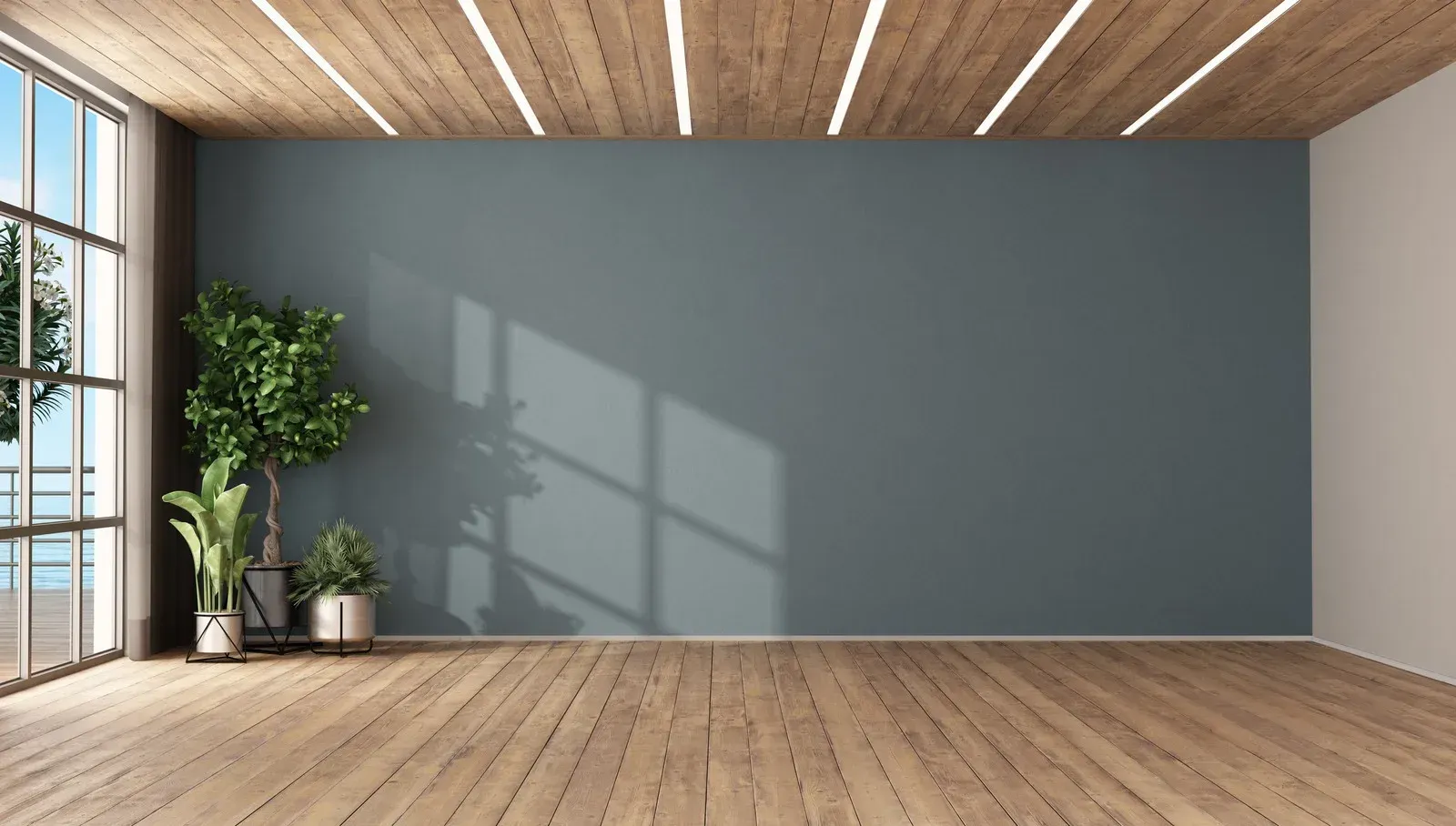 An empty room with a wooden floor and a gray wall.