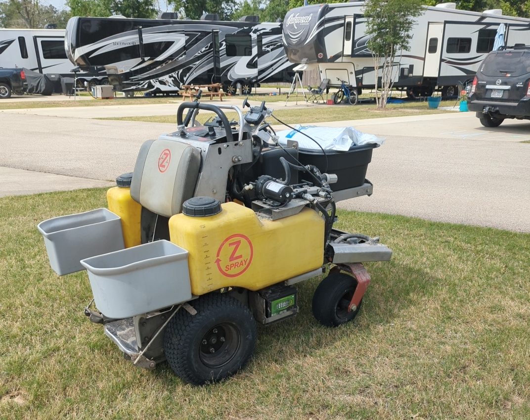 A yellow and gray lawn mower is parked in the grass.