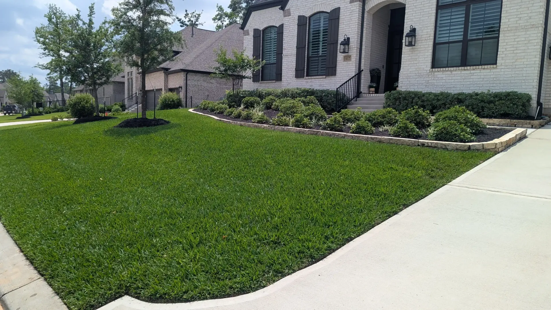 A white house with a lush green lawn in front of it