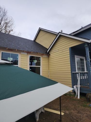 A blue and yellow house with a green umbrella in front of it.
