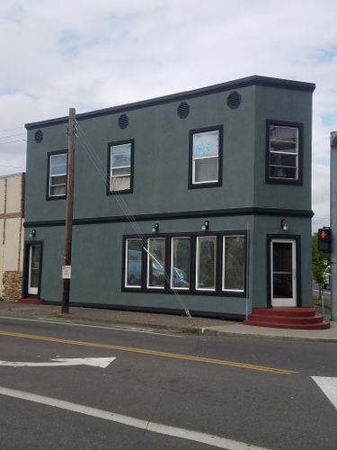 A building with a lot of windows is on the corner of a street.