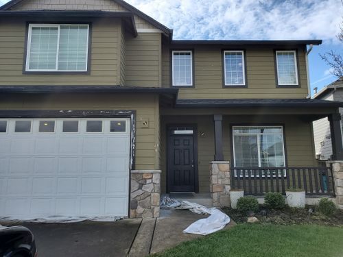 A house with a garage door and a porch is being painted.