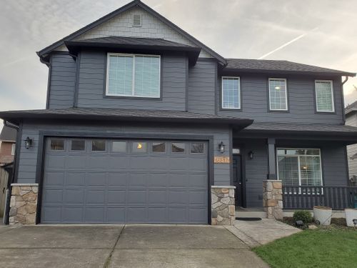 A large gray house with a large garage door.