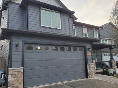 A large gray house with a large garage door.