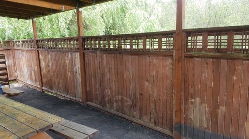 A wooden fence with a picnic table in front of it.