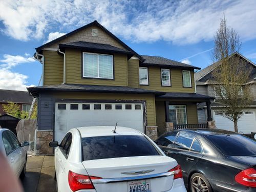 A white car is parked in front of a large house.