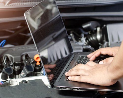 Detail of a mechanic using electronic diagnostic equipment to tune a car