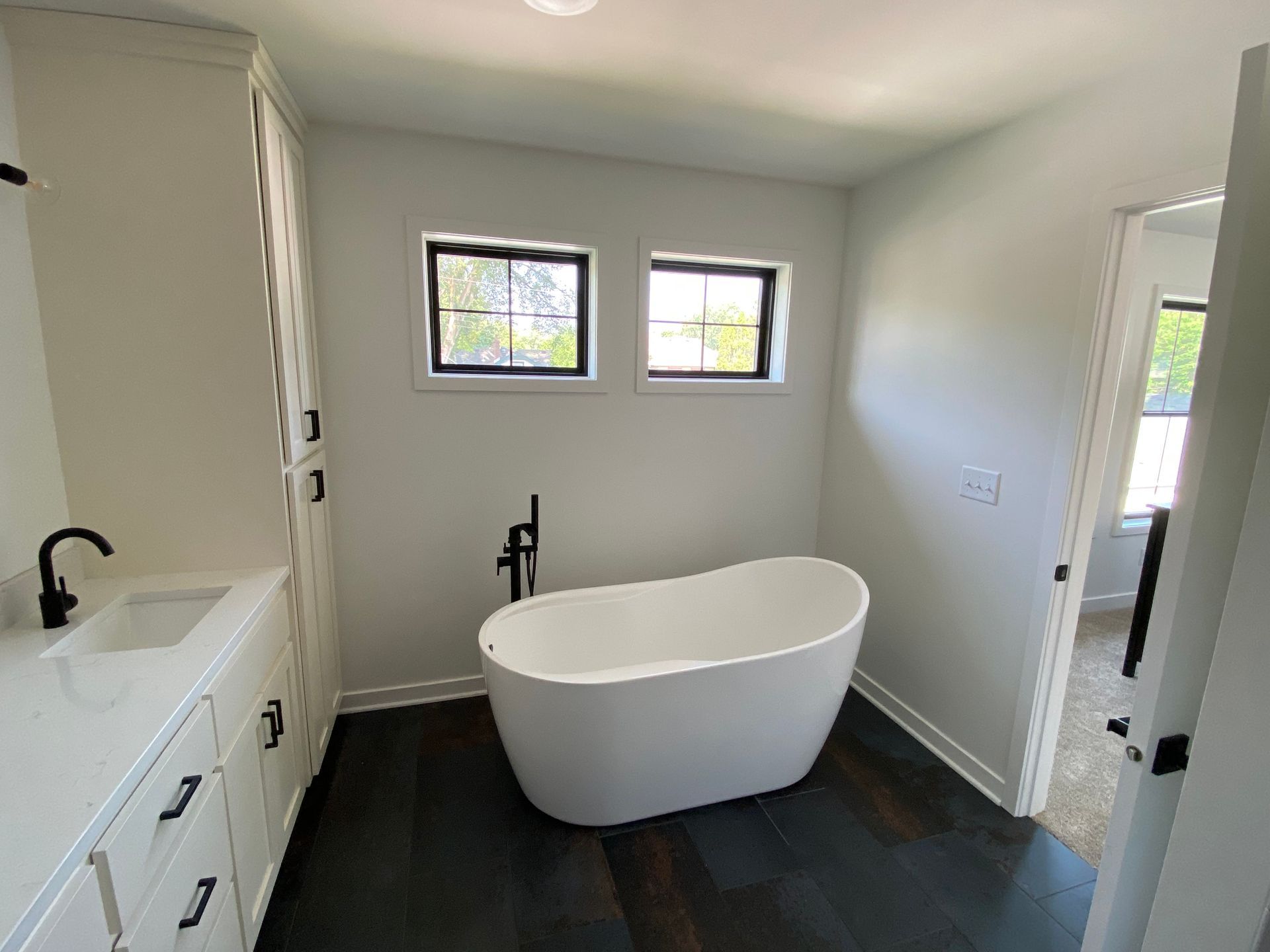 Modern kitchen with gray island, white cabinets, stainless steel appliances, and open layout to dining and living areas.