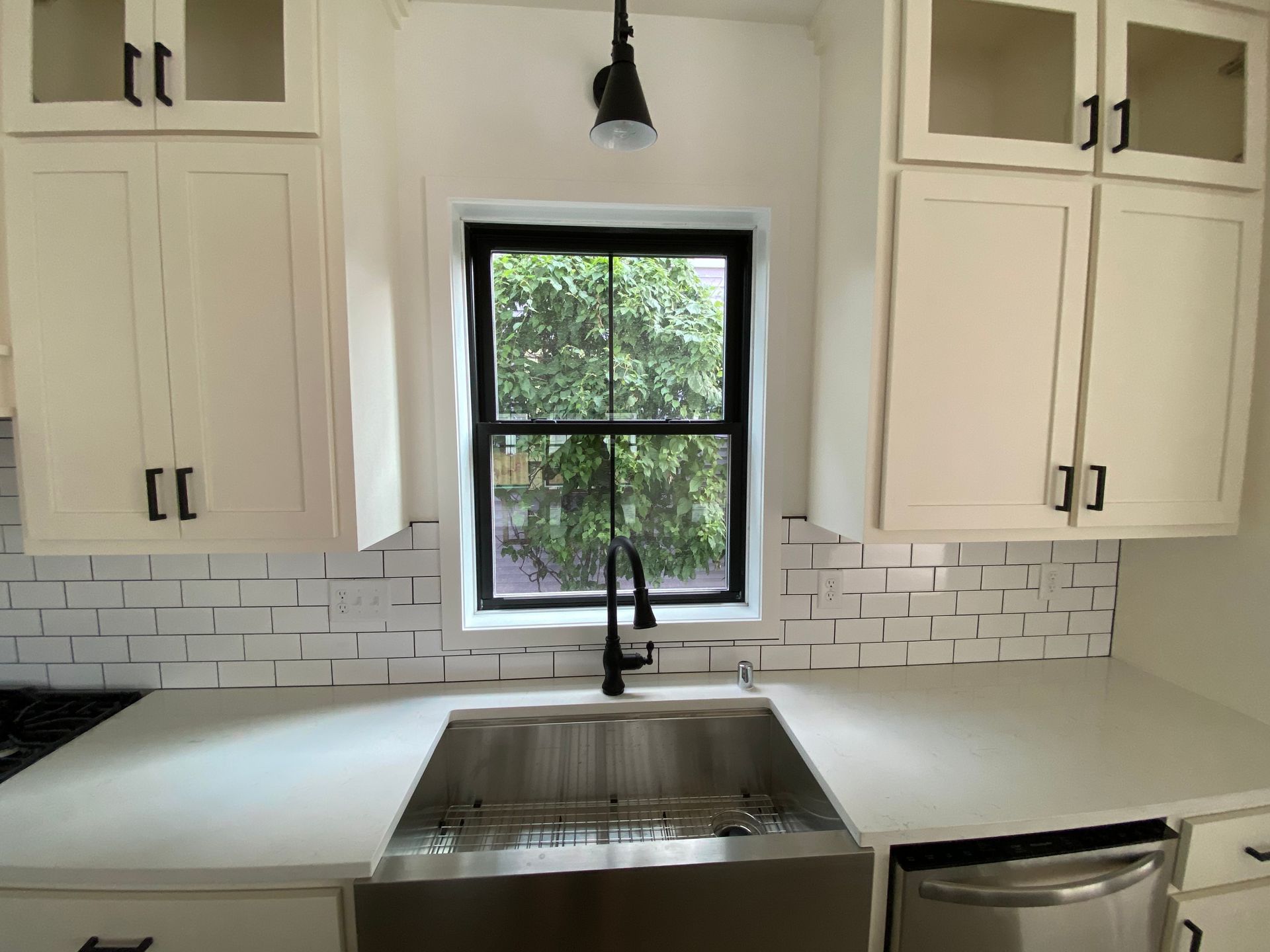Two-story house with white brick exterior, dark windows, and manicured lawn.