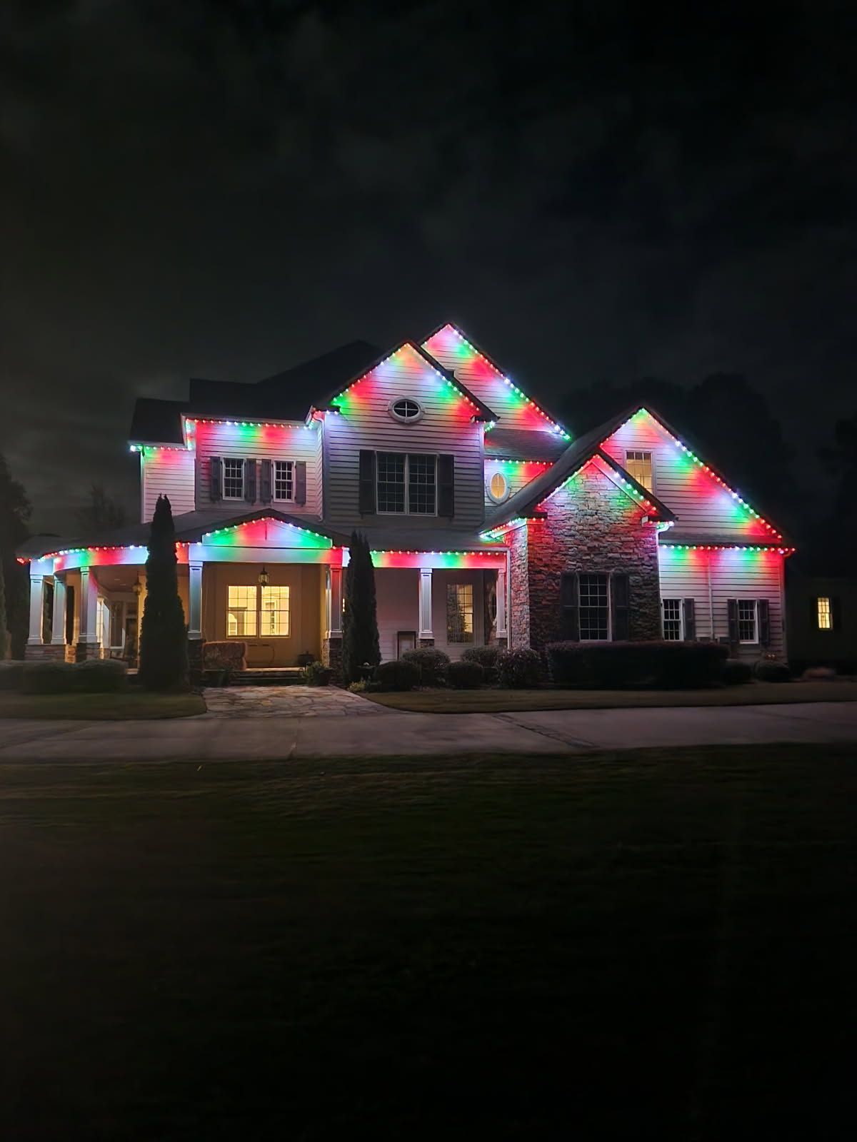 House decorated with colorful Christmas lights against a dark night sky.