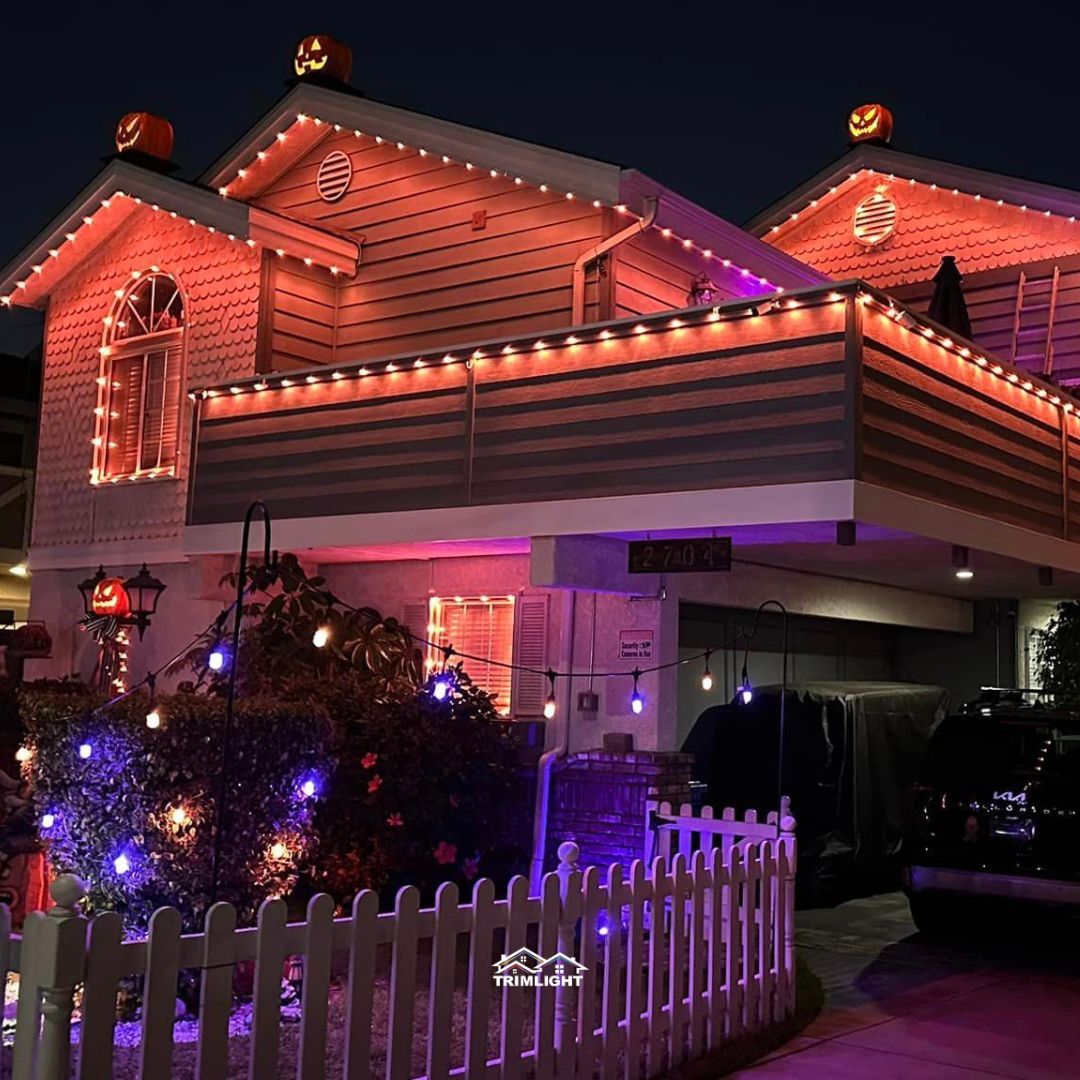 House decorated for Halloween with orange and purple lights and pumpkins.