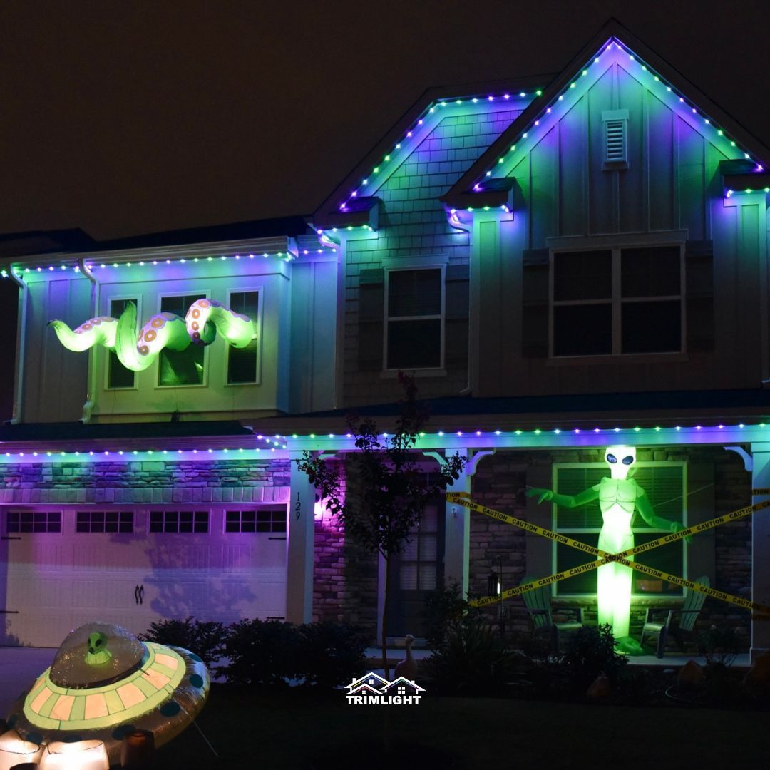 House decorated for Halloween with green and purple lights, an alien display, and a UFO.