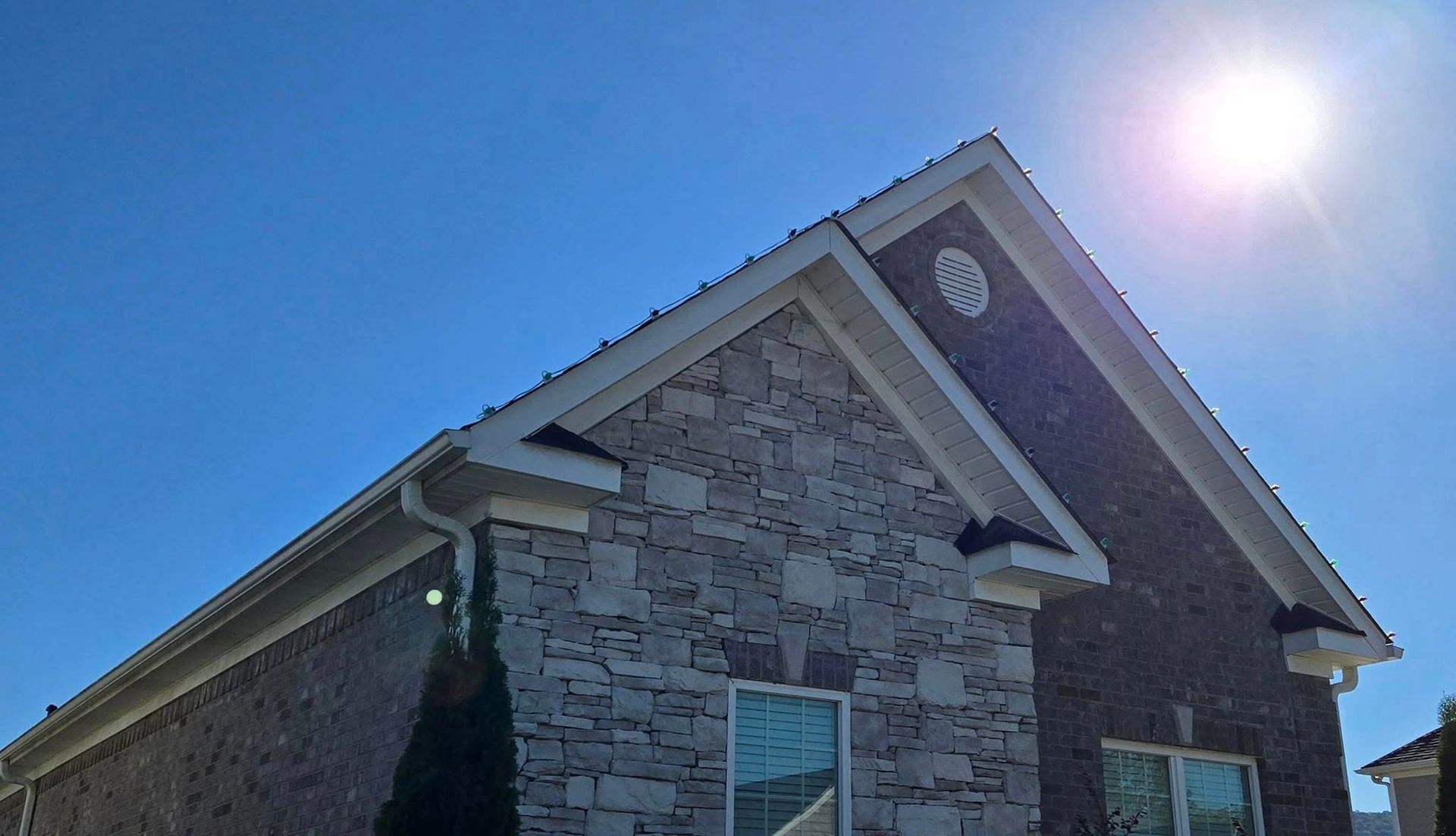 Brick house exterior with stone accent, blue sky, and bright sun.