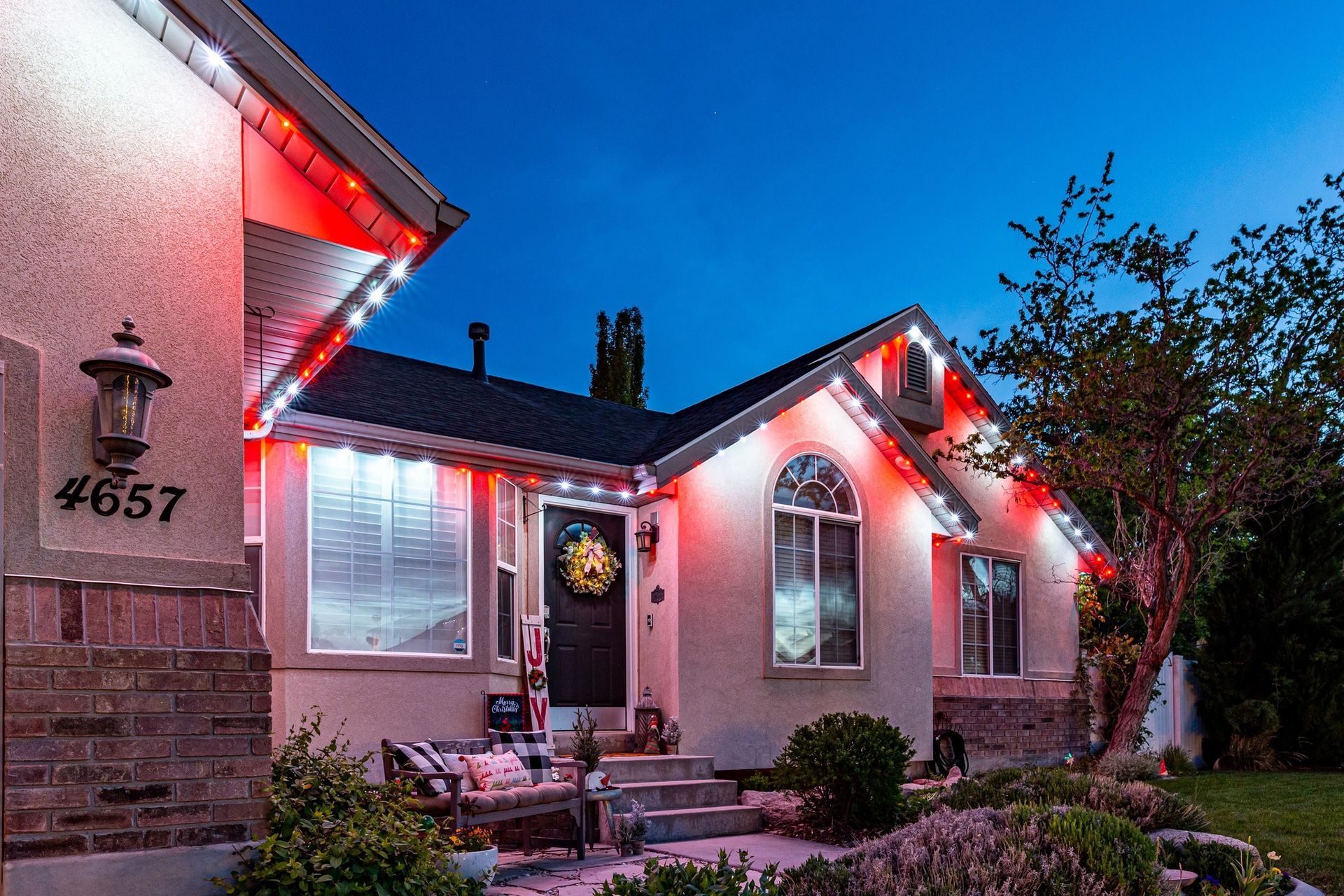 House exterior at night, lit with red lights. Address 