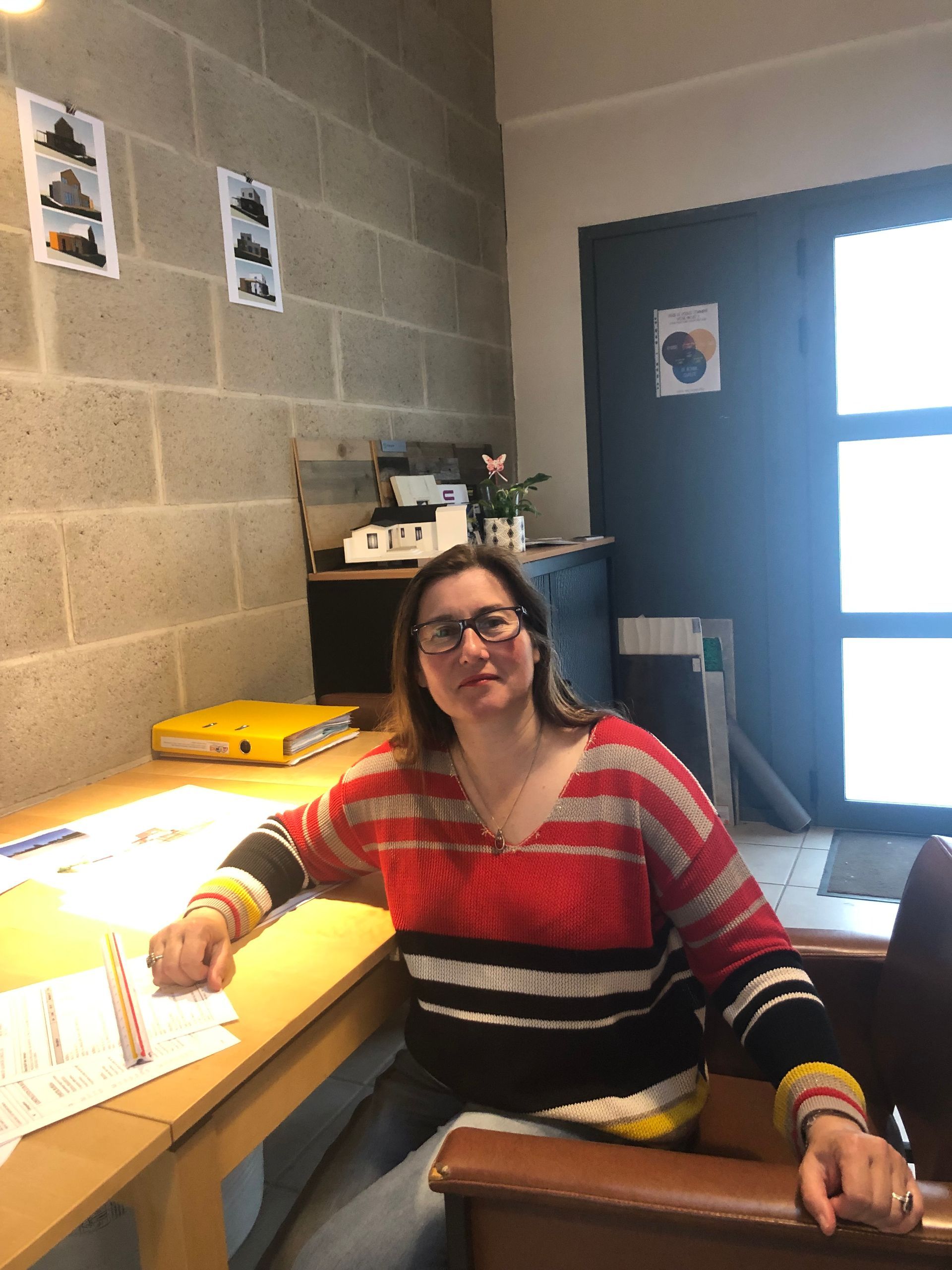 Une femme vêtue d'un pull rayé rouge et noir est assise à un bureau