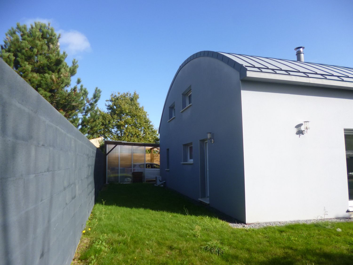 Maison grise avec jardin et mur de clôture 