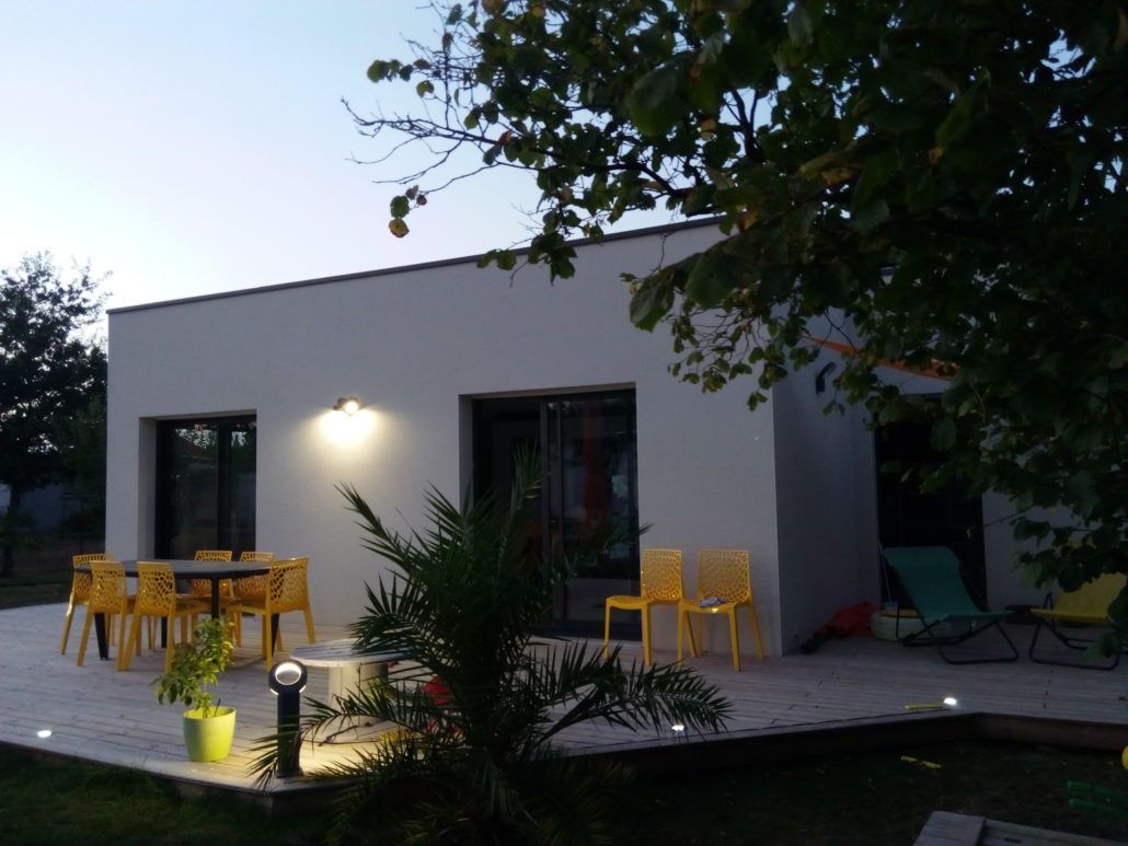 Une maison blanche avec un patio et des chaises devant