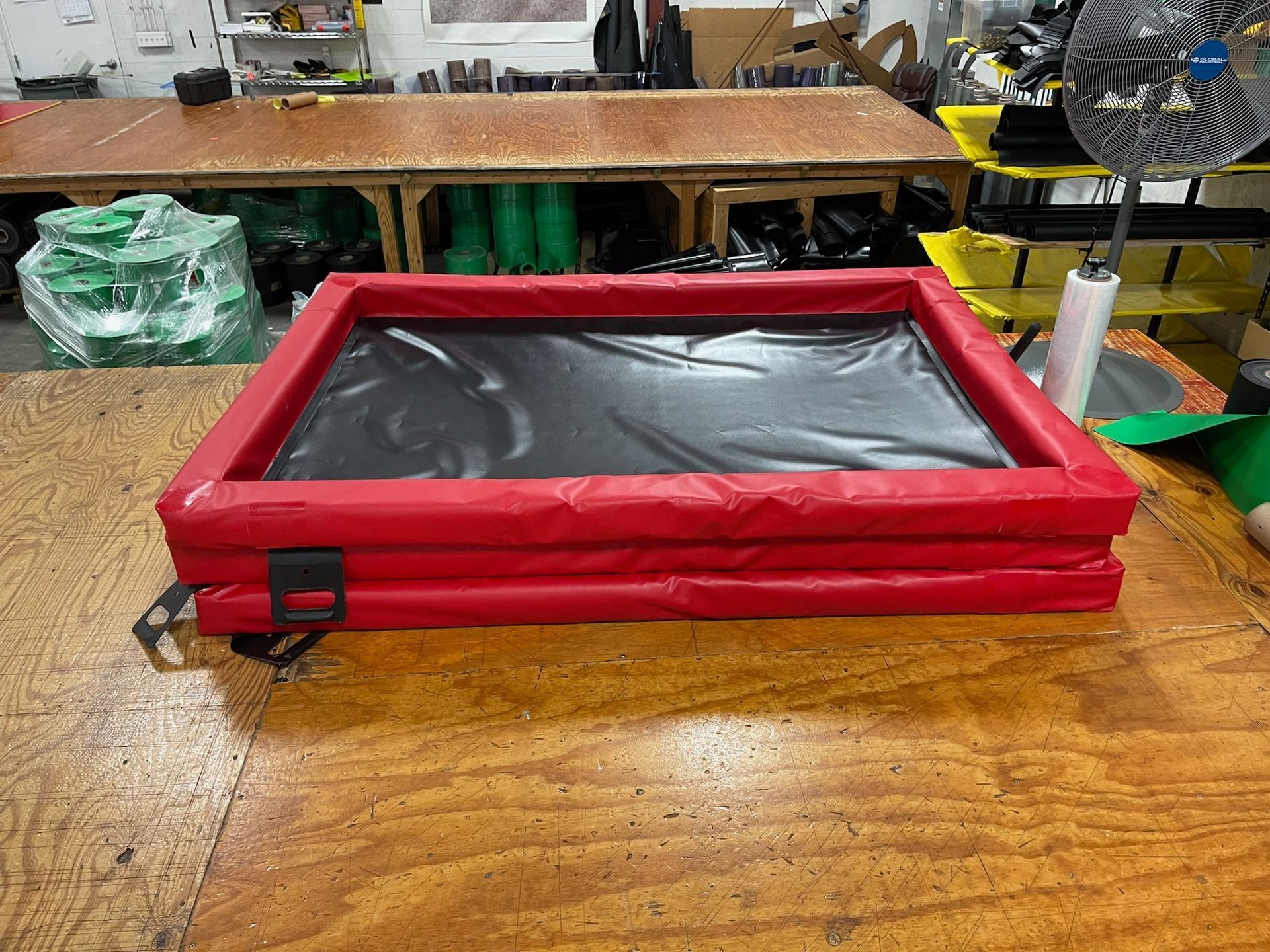 A red and black inflatable pool is sitting on top of a wooden table.