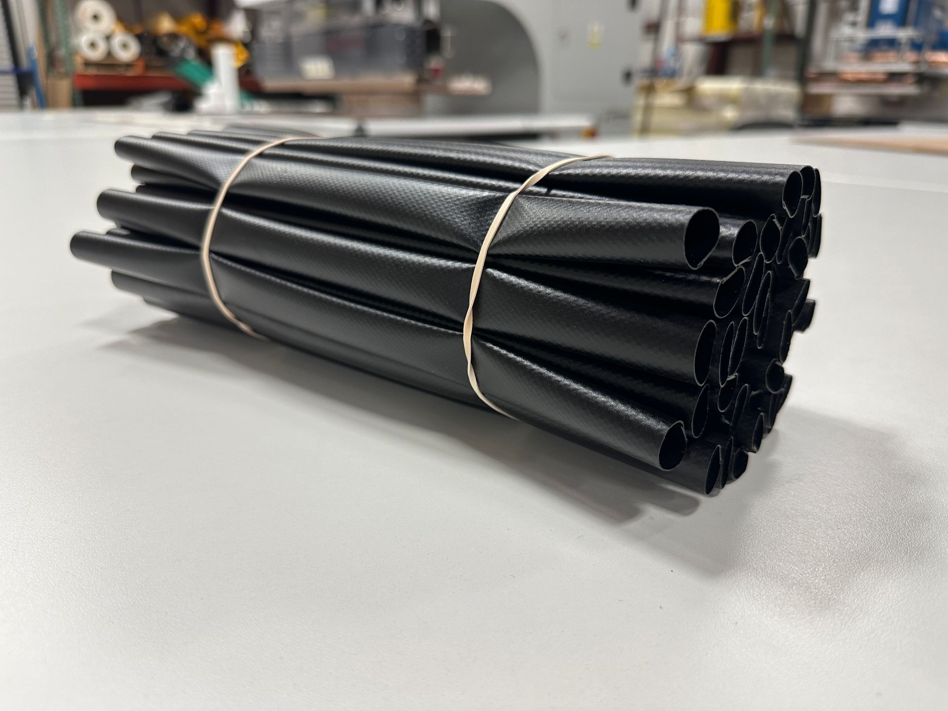 A bunch of black tubes are tied together with a rubber band on a table.