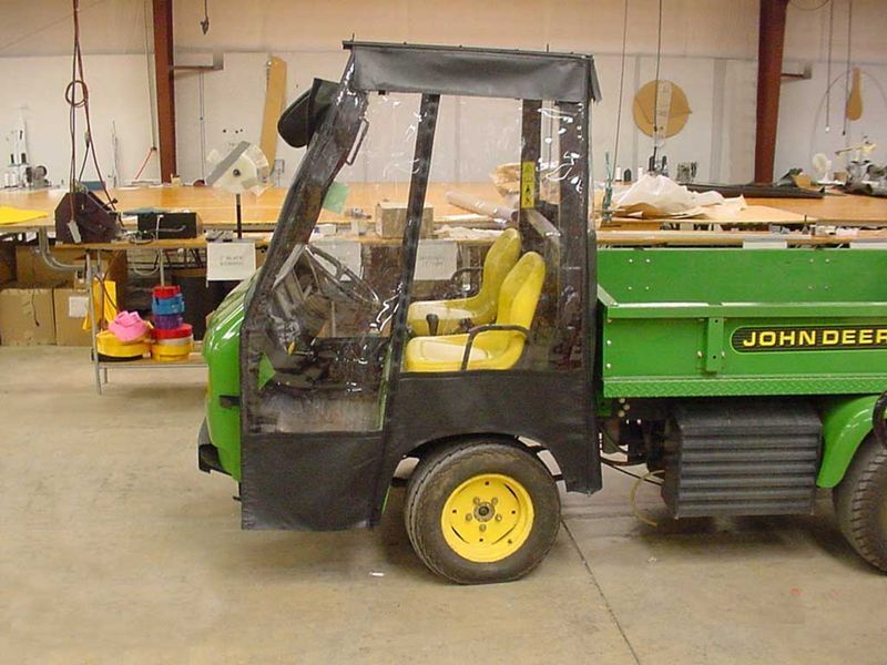 A green john deer truck is parked in a warehouse