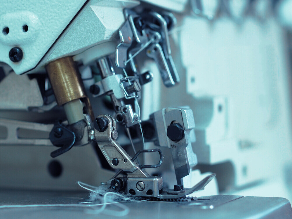 A close up of a sewing machine with a blue background.