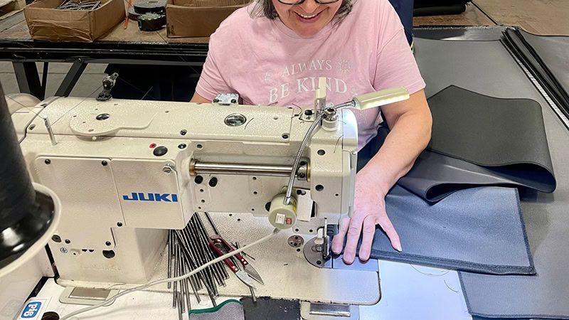 A woman is sitting at a table using a sewing machine.