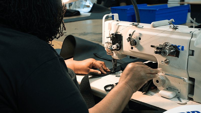 A woman is using a sewing machine in a factory.