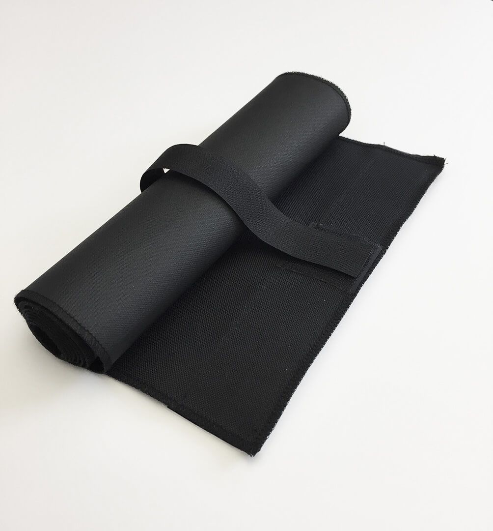 A black towel is rolled up on a white surface