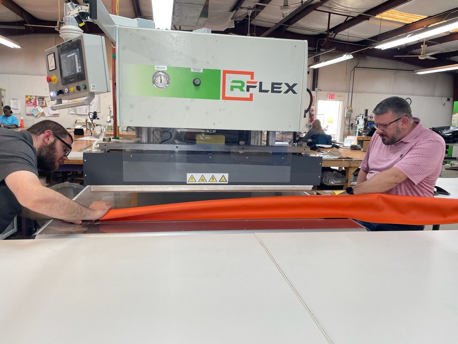 Two men are working on a machine in a factory.