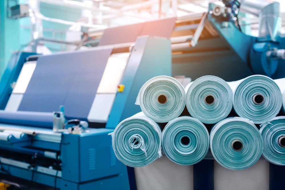 Rolls of fabric are stacked on top of each other in a factory.