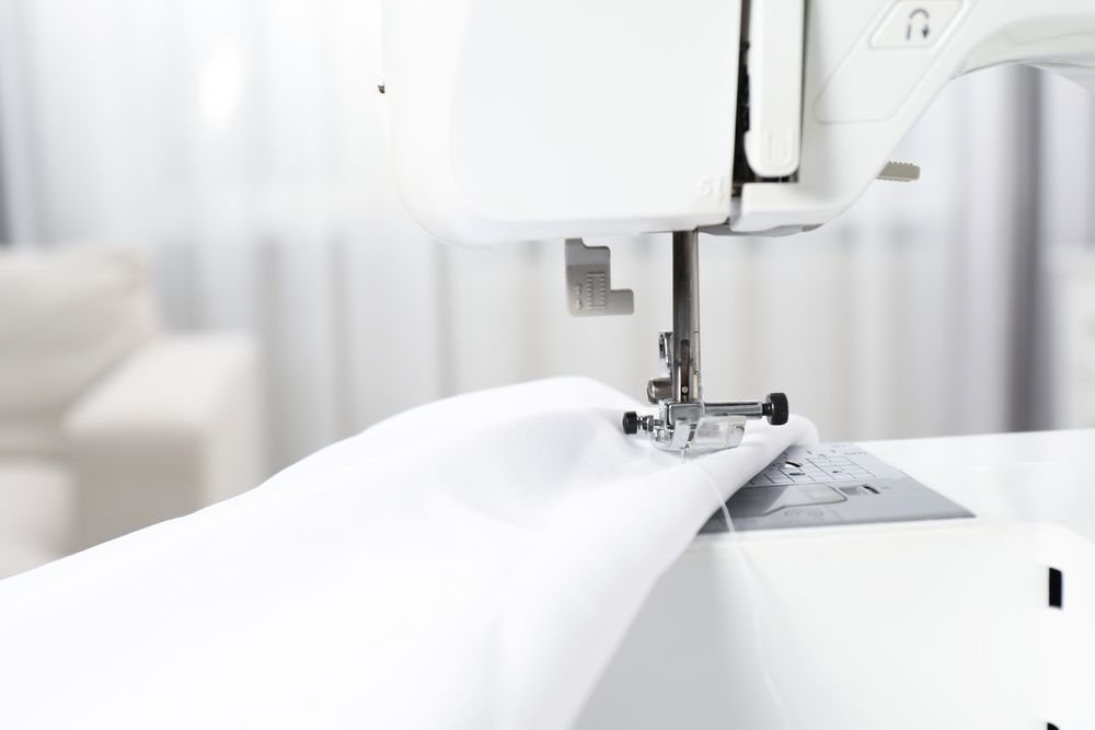 Sewing machine stitching white fabric.