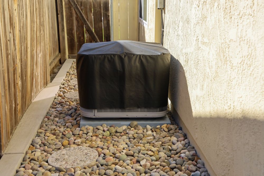 A black cover is covering an air conditioner in a rocky area