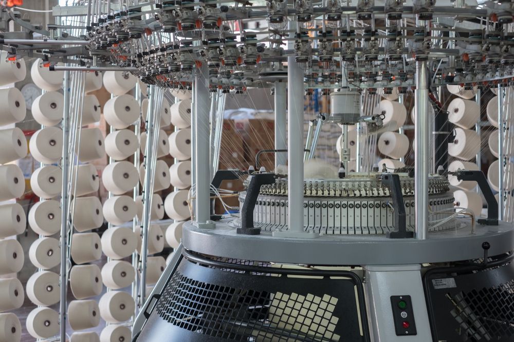 A machine is sitting in front of a wall of yarn.