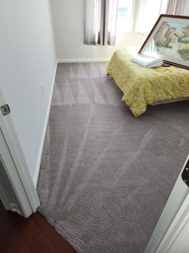 Small bedroom with gray carpet, white walls, and a bed covered in yellow bedding near a window.