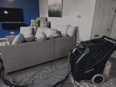 Living room with a gray couch, TV, and a black vacuum cleaner on the floor