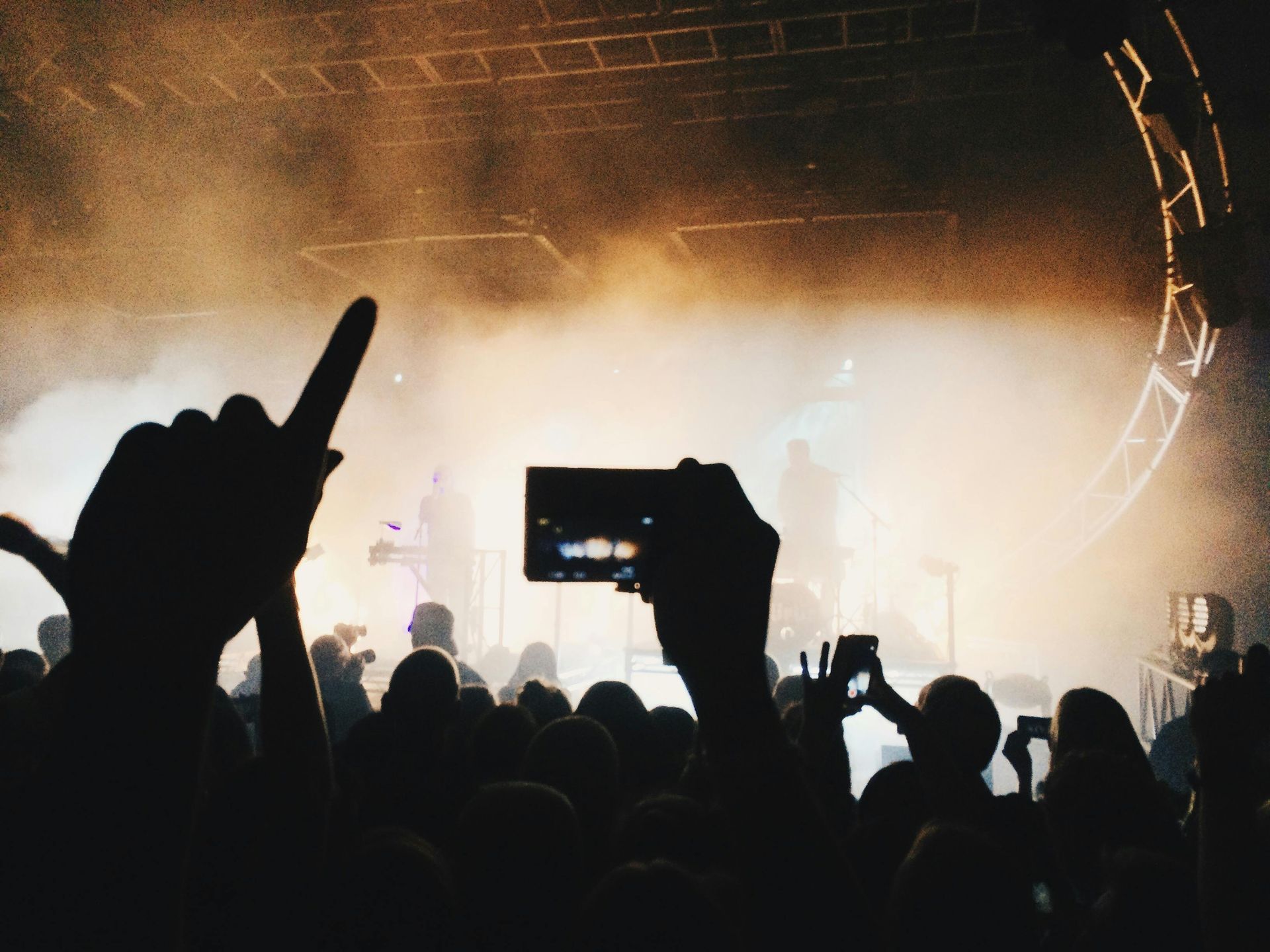 A crowd of people watching a concert with their hands in the air