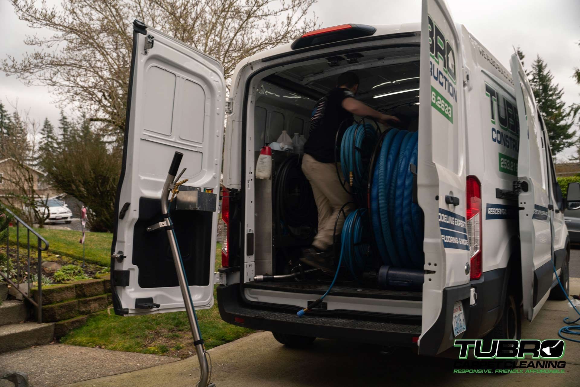 A man is standing in the back of a white van with the door open.