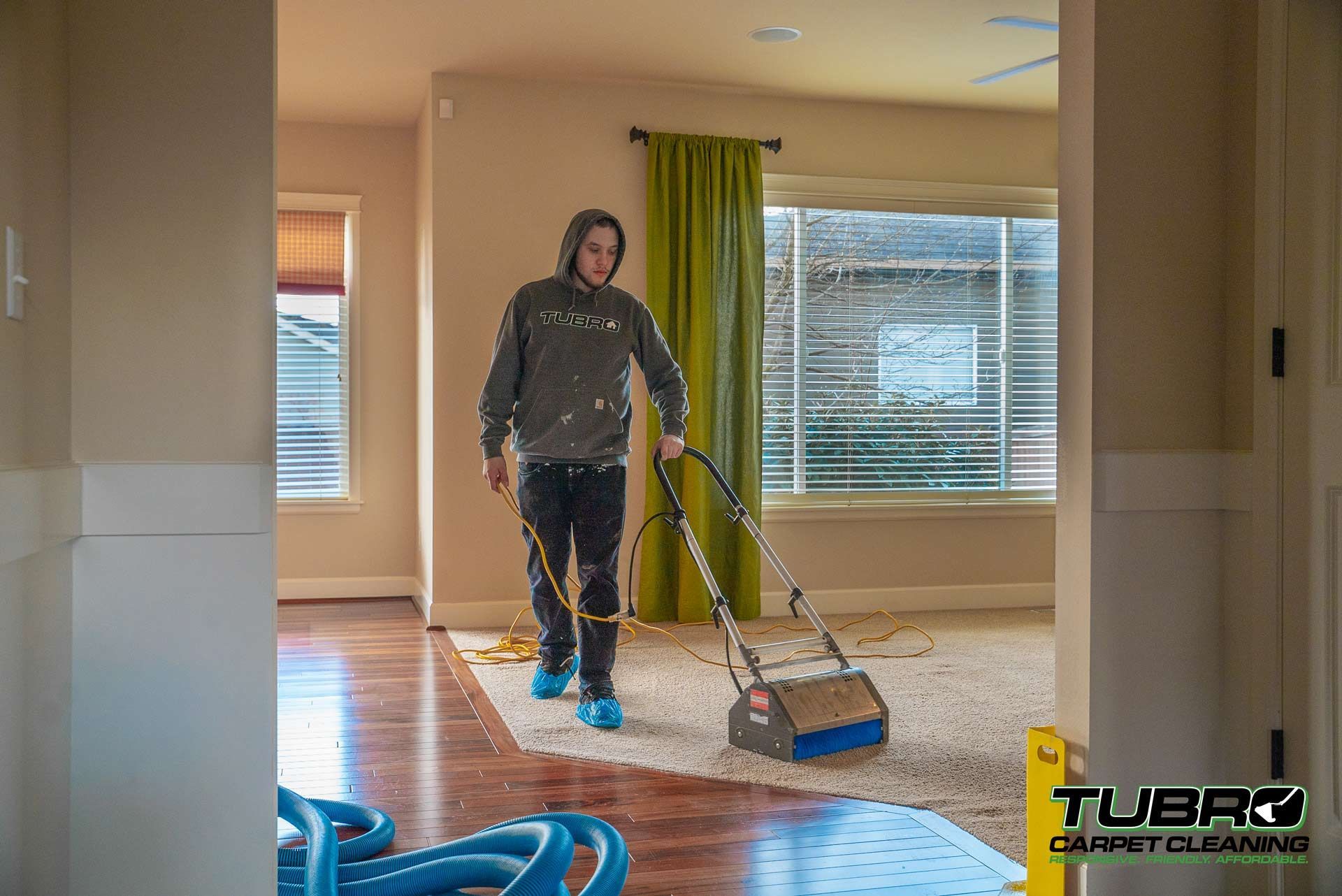 A man is using a vacuum cleaner to clean a carpet in a living room.
