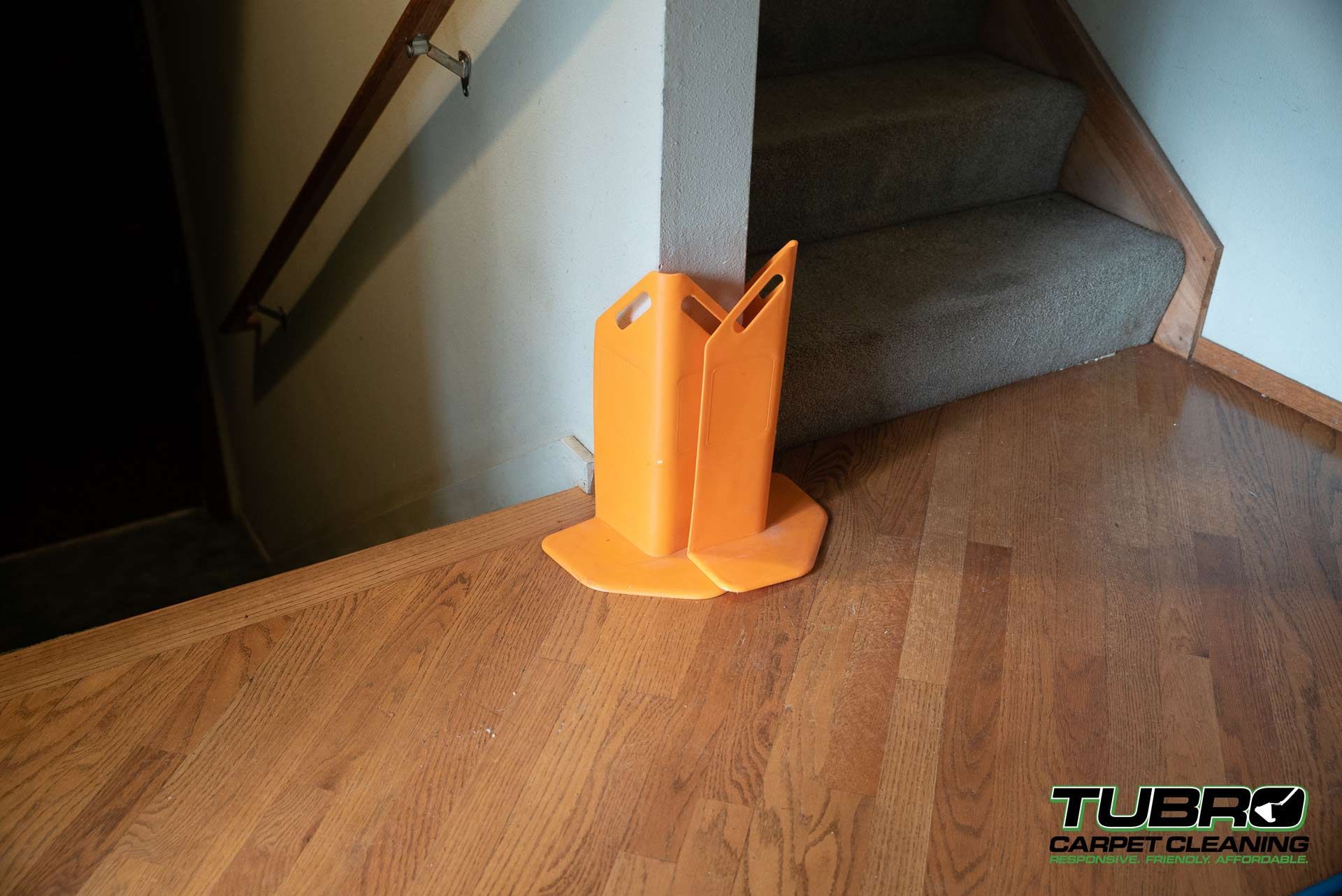An orange object is sitting on a wooden floor next to a staircase.