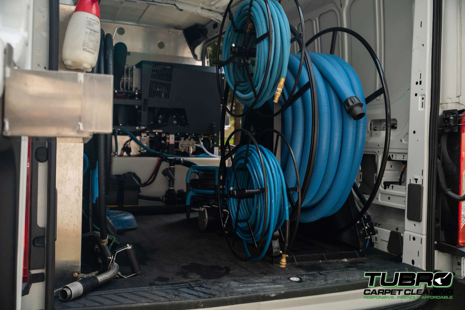 A van with a bunch of hose spools in the back.