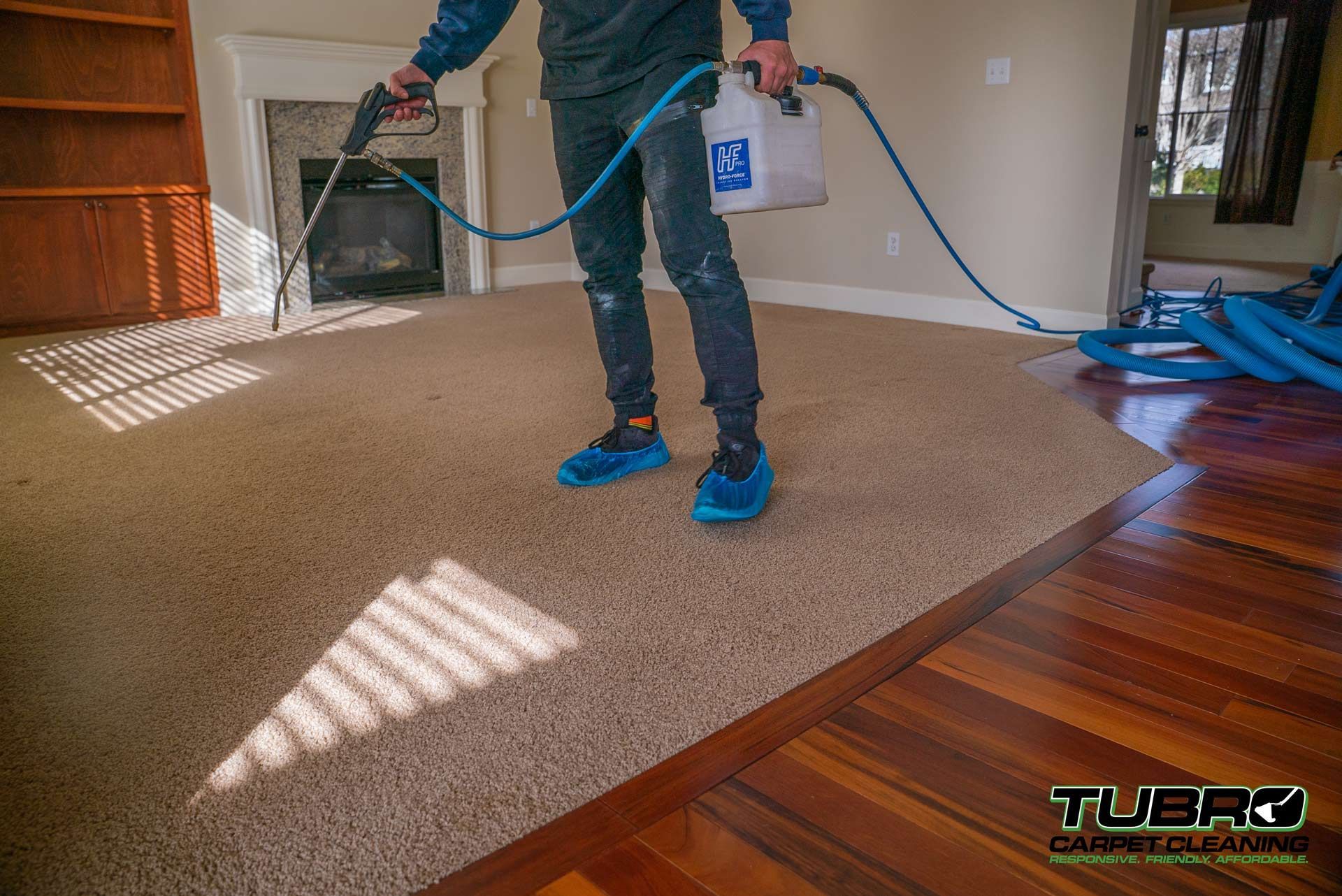 A man is cleaning a carpet in a living room with a vacuum cleaner.