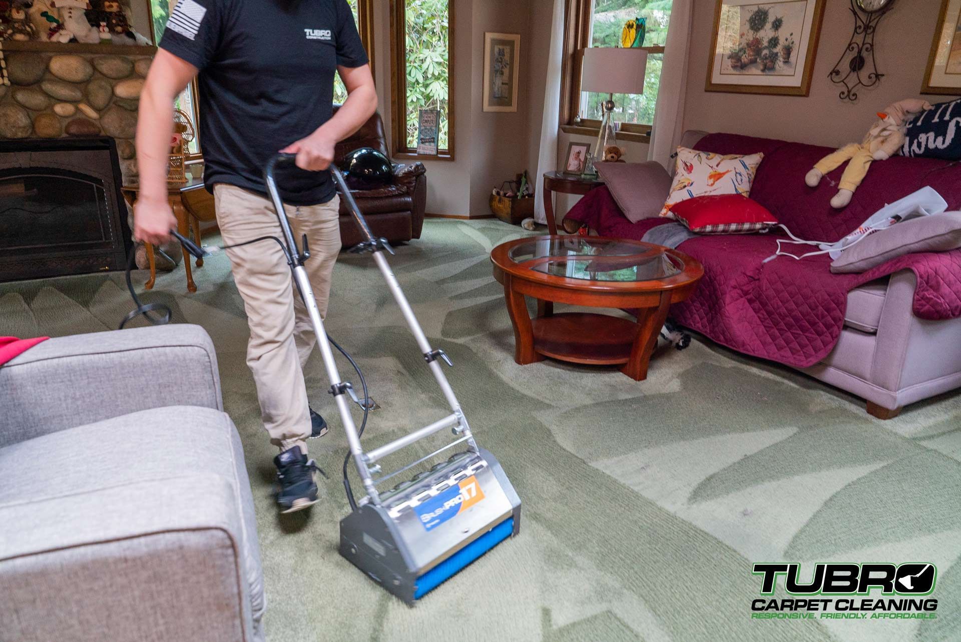 A man is cleaning a carpet in a living room with a machine.