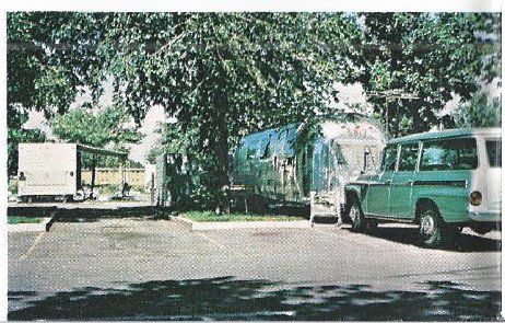 A green truck and a white van are parked in a parking lot