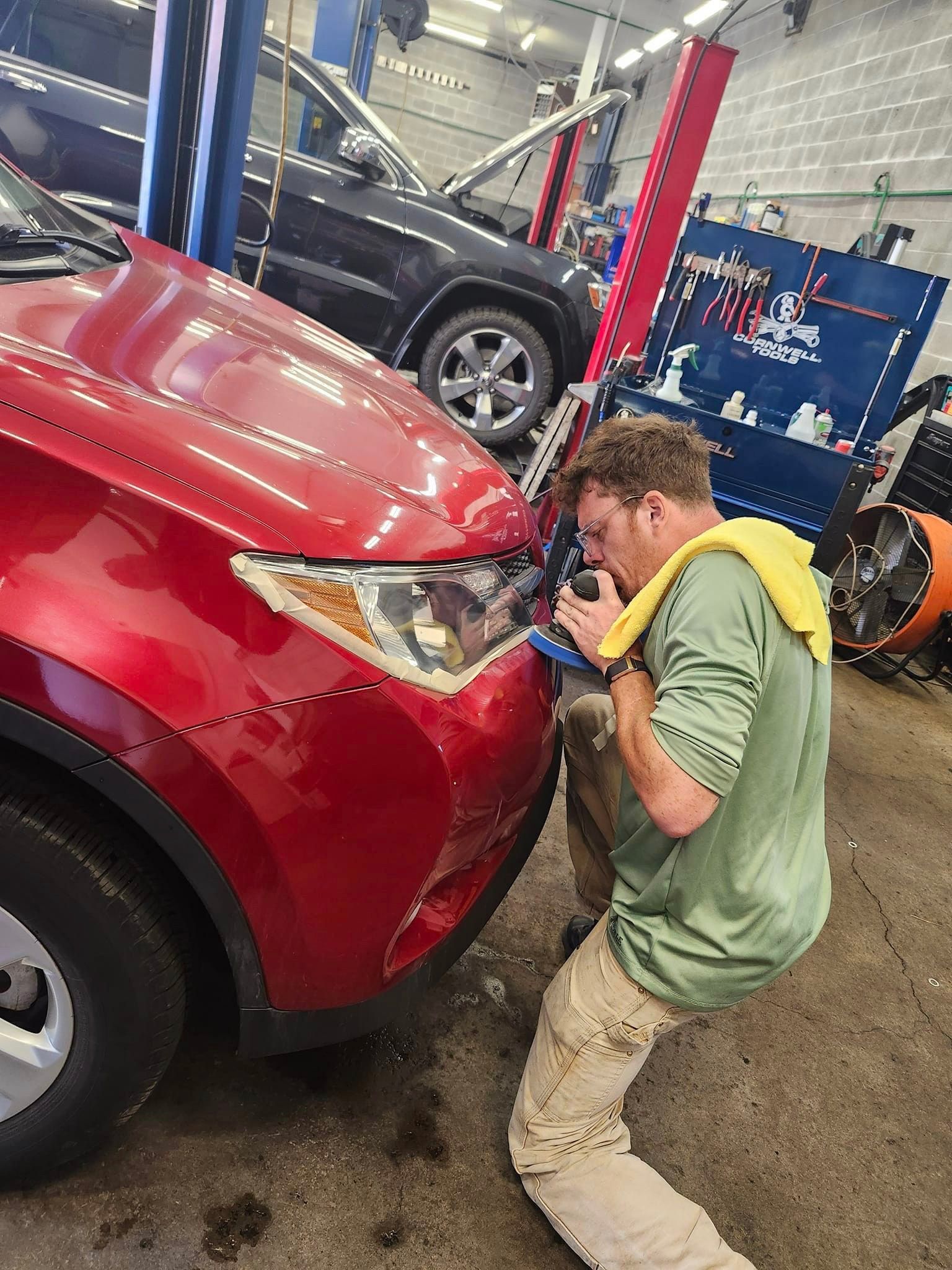 A man is working on a red car in a garage.| Oakmont Service Center