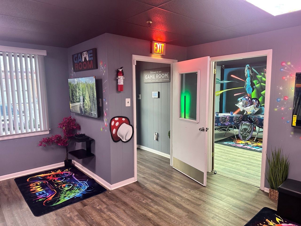 An office room with video game themes. Includes a TV, artwork, and a rug with a colorful design.