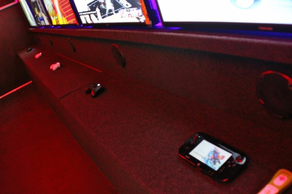 Wii U gamepad on a dark surface, near slots and screens; red lighting, tech setup.