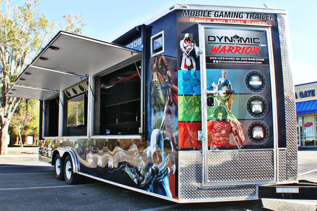 Gaming trailer with open side, graphics of video game characters, parked outdoors.